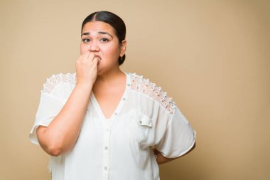 Nervous overweight woman feeling anxious and biting her nails because of the stress or a scary situation