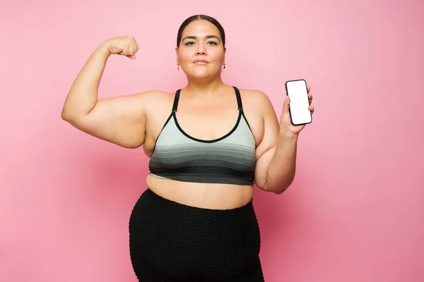 Determined Serious Overweight Woman Doing Bicep Curl Using Fitness App — Fotografia de Stock