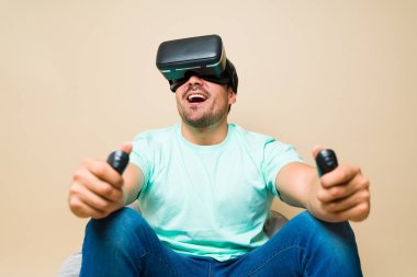 Attractive latin man looking surprised and joyful while playing a virtual reality video game with glasses 