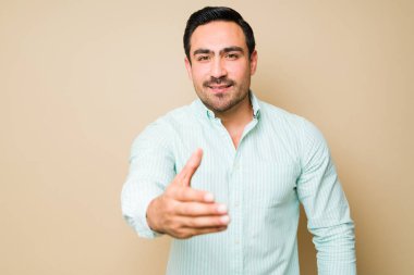 Handsome young man smiling and feeling positive emotions while shaking hands during a meeting with a person