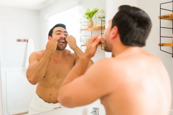 Male grooming concept. Handsome shirtless man with dental hygiene flossing his teeth after using a toothbrush and taking a shower