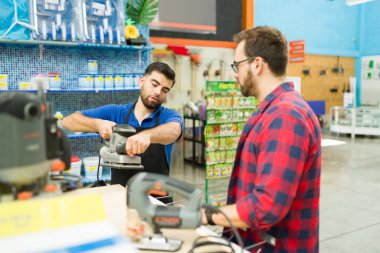 Caucasian employee showing the power tools to a male customer while working at the hardware store