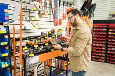 Thoughtful caucasian man or carpenter considering buying a new saw or construction tools while shopping at the hardware store