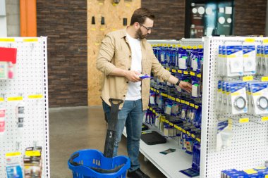 Handsome man in his 20 buying a new switch at the hardware store while doing a home improvement project 