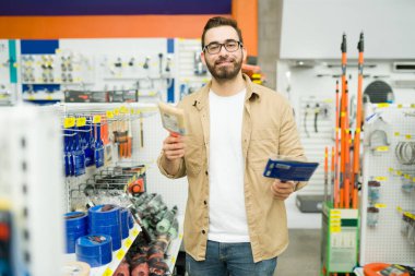 Portrait of a happy attractive man smiling and making eye contact at the hardware store while shopping for brushes to paint his house 