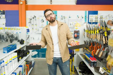 Indecisive stressed man feeling upset and needs help to choose the best brush to buy at the hardware store