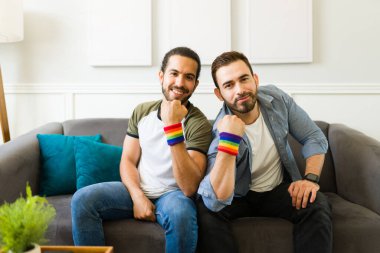Multiracial gay men smiling while wearing rainbow wristbands and supporting LGBT rights 