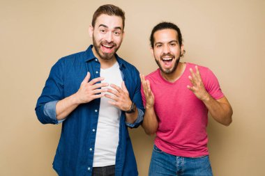 Very excited gay couple shouting with happiness and looking surprised after receiving good news 