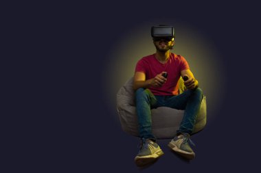 Hispanic young man playing a virtual reality video game against a futuristic background with copy space
