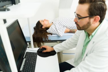 Technician at the imaging diagnostic lab doing a densitometry scan medical test to check the bones of a young woman