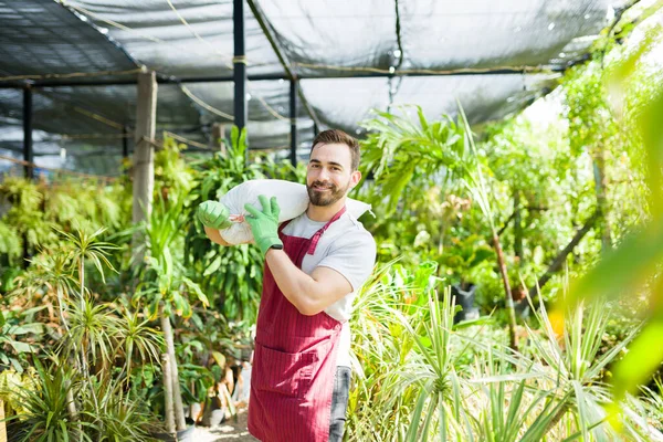 Portrait of a handsome worker and gardener smiling and looking happy while working at a beautiful nursery garden