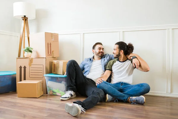Multiracial handsome gay couple embracing after bringing the boxes to the new apartment while moving in together