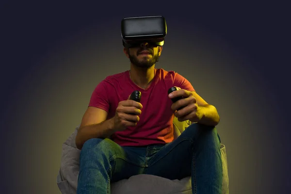 Attractive latin man using immersive technology playing a virtual reality videogame on a comfy bean bag