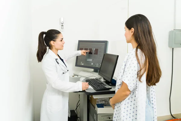 Caucasian female radiologist showing the medical results of the mammography to a young female patient to check for breast cancer