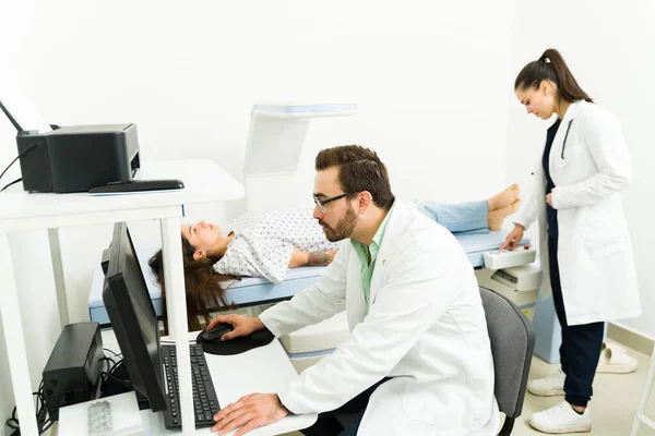 Radiologist and doctor at the diagnostic lab doing a densitometry scan on a sick female patient to examine her bones for cancer