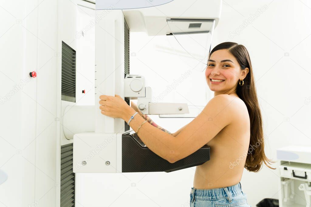 Portrait of a happy hispanic woman at the imaging diagnostic lab smiling while getting a mammogram during a breast cancer awareness program