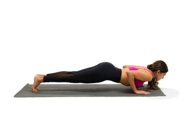 Side view of an active young woman on a four limbed staff pose on an exercise mat during her yoga workout
