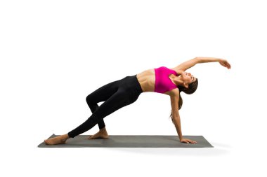 Strong fit young woman practicing a wild things pose while training yoga on an exercise mat