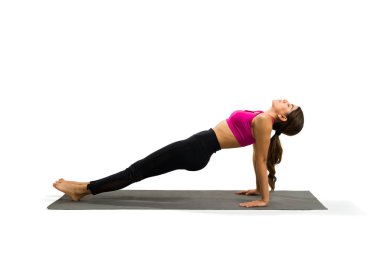 Attractive latin woman in activewear doing a reverse plank while working out with yoga exercises 