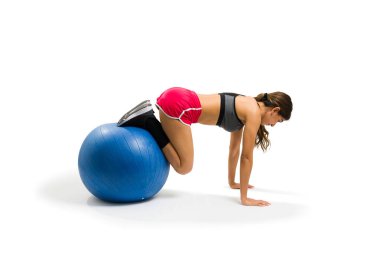Active latin woman making a plank using a stability ball and exercising over a white background