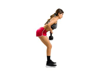 Fit strong woman preparing to do squat exercises while lifting a kettlebell weight during her cross training
