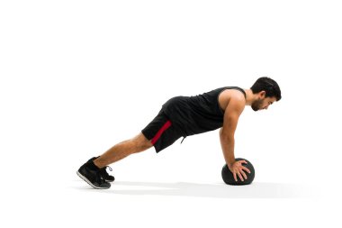 Sporty hispanic man doing push up exercises for his cross training workout and using slam ball
