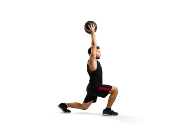 Attractive hispanic man in sportswear using a slam ball while exercising with leg lunges isolated on a white background
