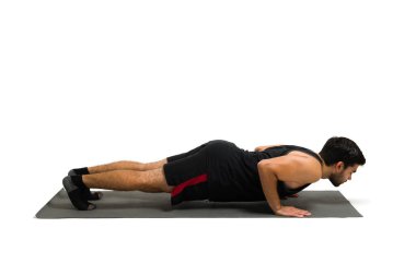 Side view of an active young man on a four limbed staff pose on an exercise mat during his yoga workout