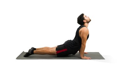Attractive latin man training yoga and doing an upward facing dog on an exercise mat 