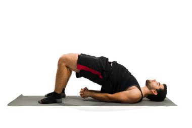 Attractive fit hispanic man with a healthy lifestyle working out and doing a bridge pose during his yoga training 