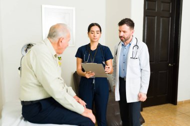Doctor and nurse doing a medical exam to  sick mature elder patient at the nursery home