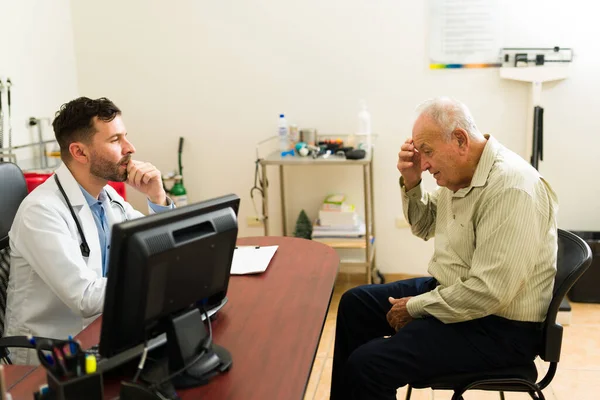 Concerned doctor talking with a sick elder man in his 80s about his sickness and symptoms during a medical check up