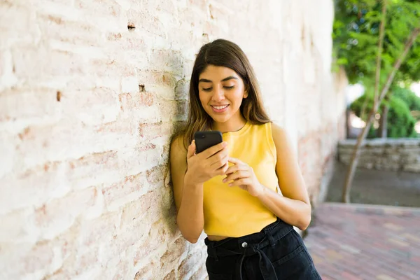 Smiling Young Woman Smiling While Texting Her Smartphone While Standing — Stock Photo, Image