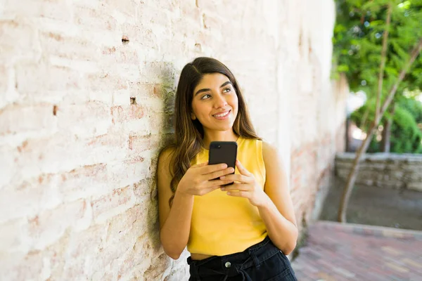 有思想的女人在用智能手机发短信或在户外使用社交媒体时 会思考和运用自己的想象力 — 图库照片