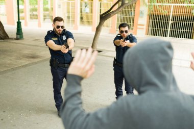 Bir suç işledikten sonra polis tarafından tutuklanırken ellerini kaldıran bir soyguncunun arka görüntüsü.