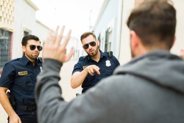 Sokakta polis memurları tarafından tutuklanırken bir soyguncunun ellerini havaya kaldırması. 