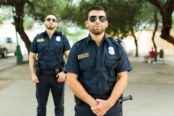 Police officers with sunglasses wearing a black uniform on duty fighting crime in the streets