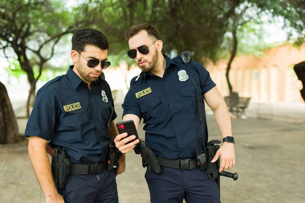 Policjanci Okularach Przeciwsłonecznych Oglądający Sms Lub Raport Kryminalny Smartfonie Podczas — Zdjęcie stockowe