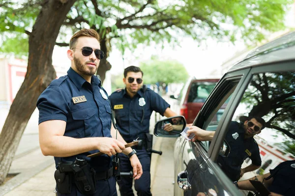Atraktivní Policisté Hledící Kamery Zatímco Řidič Snaží Podplatit Penězi Pokutu — Stock fotografie
