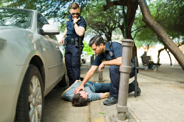 경찰관들은 자동차 사고에 부상을 남자가 있는지 살피고 있을까 염려하고 — 스톡 사진