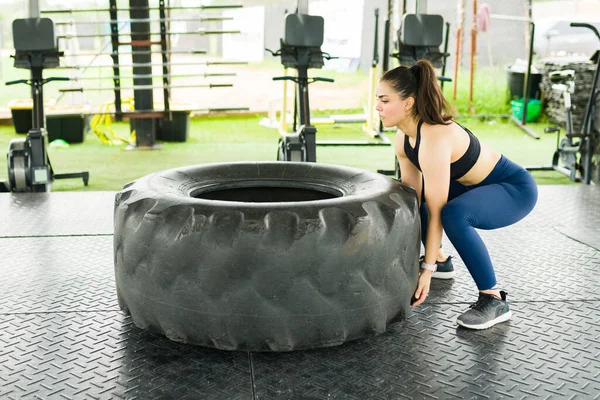 선수인 여자는 체육관에서 타이어 뒤집기 운동을 크로스 트레이닝을 강하게 느낀다 — 스톡 사진