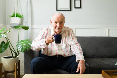 Evde dinlenirken bir fincan kahve ya da sıcak çay içen mutlu ve rahat bir son sınıf öğrencisinin portresi.