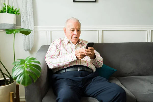 Smiling Old Man Texting Smartphone Family Friends While Relaxing Sofa — Stok Foto