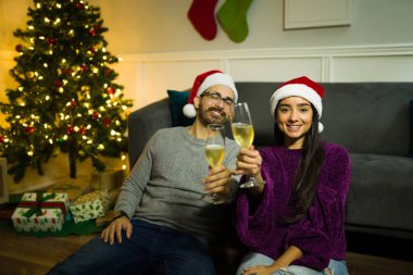 Neşeli genç kadın ve erkek evde gülümserken bir Noel gecesi şampanya içerken.