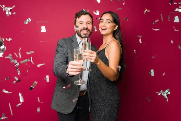 Excited smiling couple hugging and drinking champagne while enjoying a formal new year\'s party