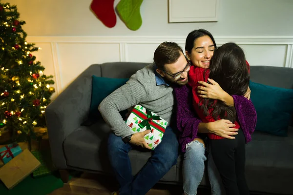 Loving Parents Hugging Cute Child Receiving Surprising Gift Christmas Holidays — Stock Photo, Image