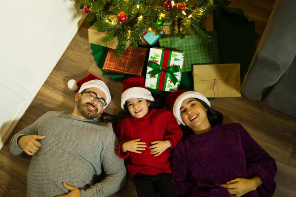 幸せな両親と若い娘は家でクリスマスの間に床で一緒に遊んでいる間笑っています — ストック写真