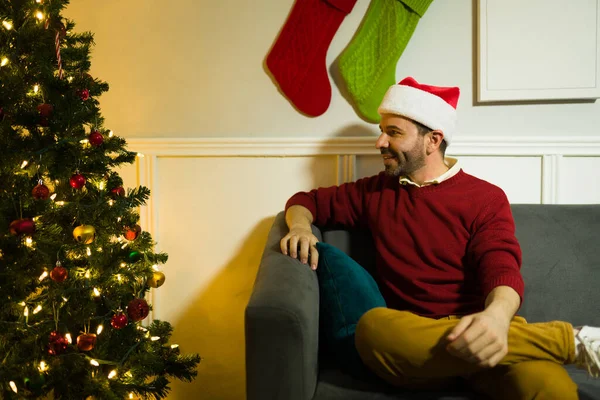 Oturma Odasındaki Noel Baba Şapkalı Rahat Genç Adam Kanepede Oturmuş — Stok fotoğraf
