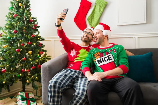 Happy Attractive Gay Couple Wearing Pajamas Santa Hats Taking Selfie — Stock Photo, Image