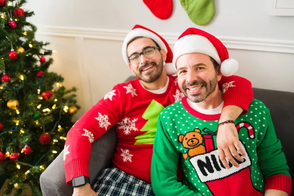 Cheerful Gay Couple Wearing Santa Hats Hugging Pajamas Looking Camera — Stock Photo, Image